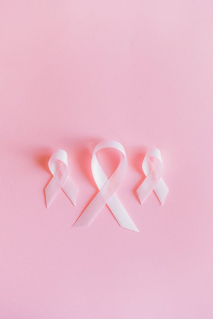 Three pink ribbons symbolize breast cancer awareness on a light pink background.